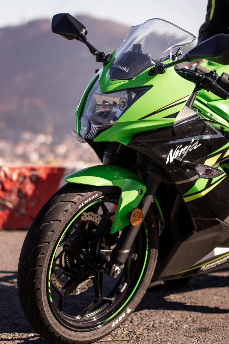 Close-up of a green Kawasaki Ninja motorcycle outdoors, showcasing its sleek design.